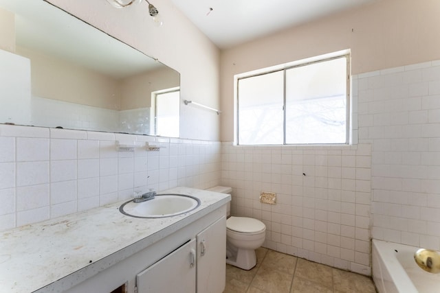 bathroom with tile patterned flooring, a tub, toilet, vanity, and tile walls