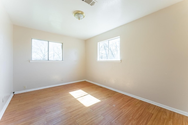 unfurnished room featuring light wood finished floors, visible vents, and baseboards