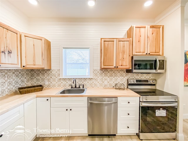 kitchen with appliances with stainless steel finishes, light hardwood / wood-style flooring, white cabinets, sink, and backsplash