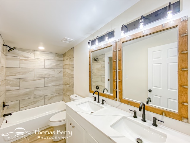 full bathroom featuring tiled shower / bath, toilet, and double sink vanity