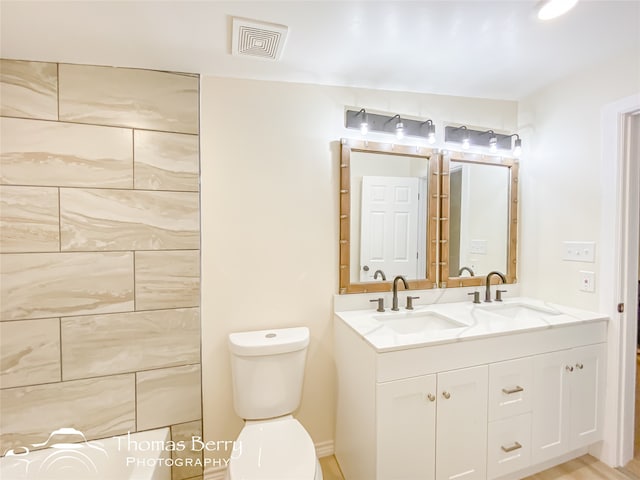 bathroom with toilet, wood-type flooring, and dual bowl vanity