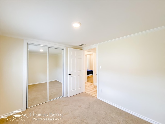 unfurnished bedroom with light carpet and a closet