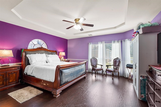 bedroom featuring a raised ceiling, ceiling fan, and dark hardwood / wood-style flooring