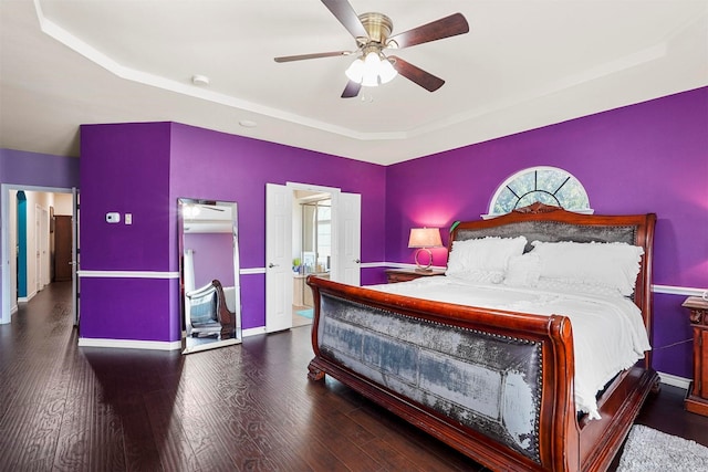 bedroom with ceiling fan, a tray ceiling, and dark hardwood / wood-style floors