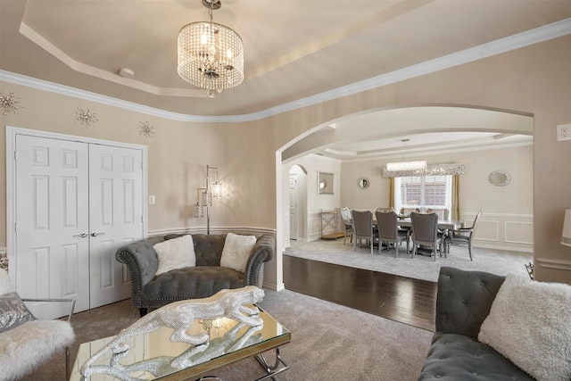 living room featuring hardwood / wood-style floors, a tray ceiling, ornamental molding, and a chandelier