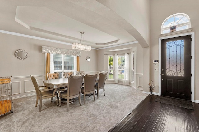 dining area featuring crown molding, a notable chandelier, a tray ceiling, and wood-type flooring