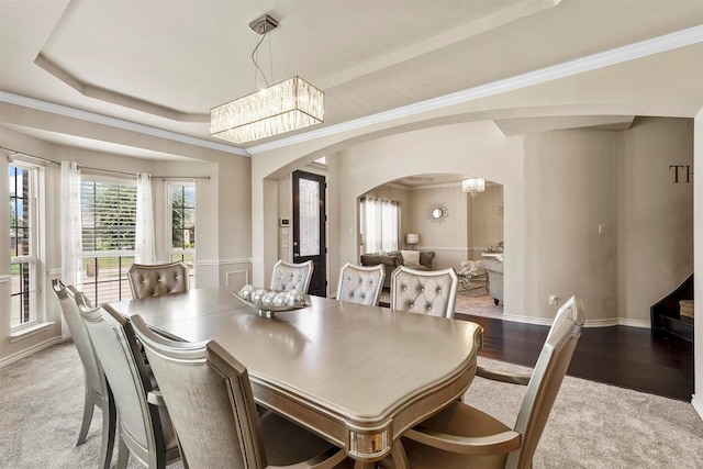 dining space with crown molding, hardwood / wood-style floors, a chandelier, and a tray ceiling