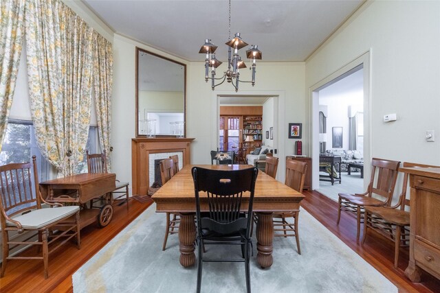 dining space with an inviting chandelier, ornamental molding, and wood-type flooring