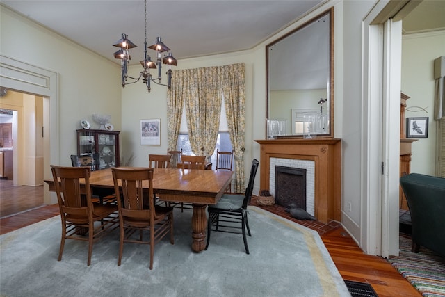 dining room with a fireplace, crown molding, dark wood-type flooring, and a chandelier