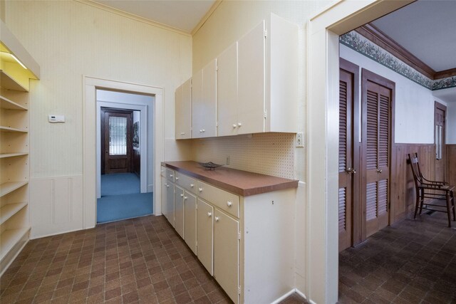 kitchen with white cabinets, crown molding, dark tile patterned floors, and decorative backsplash