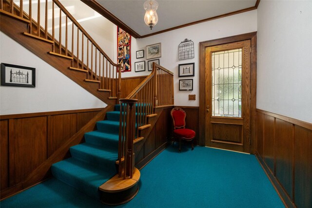 carpeted foyer featuring ornamental molding