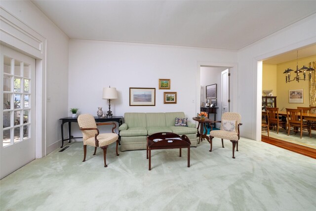 living area featuring ornamental molding, carpet floors, and a chandelier