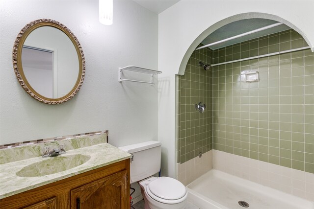 bathroom featuring vanity, tiled shower, and toilet