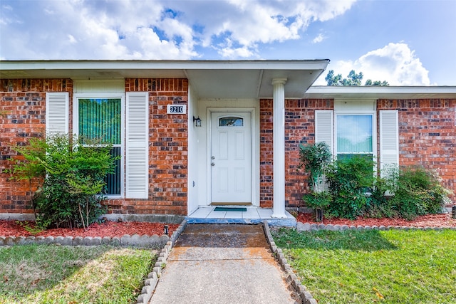 view of exterior entry with a yard