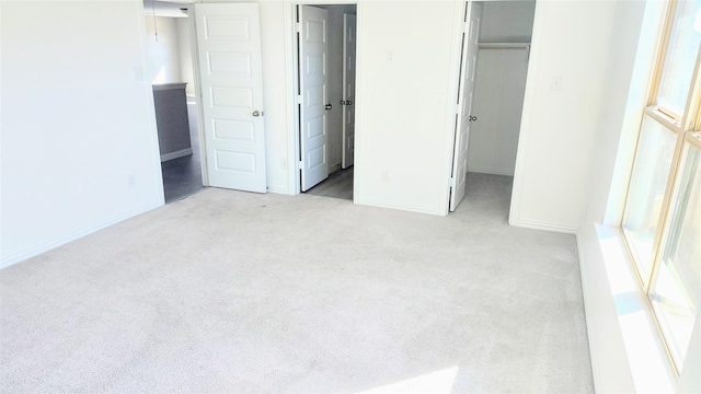 unfurnished bedroom with a walk in closet, light carpet, and a closet