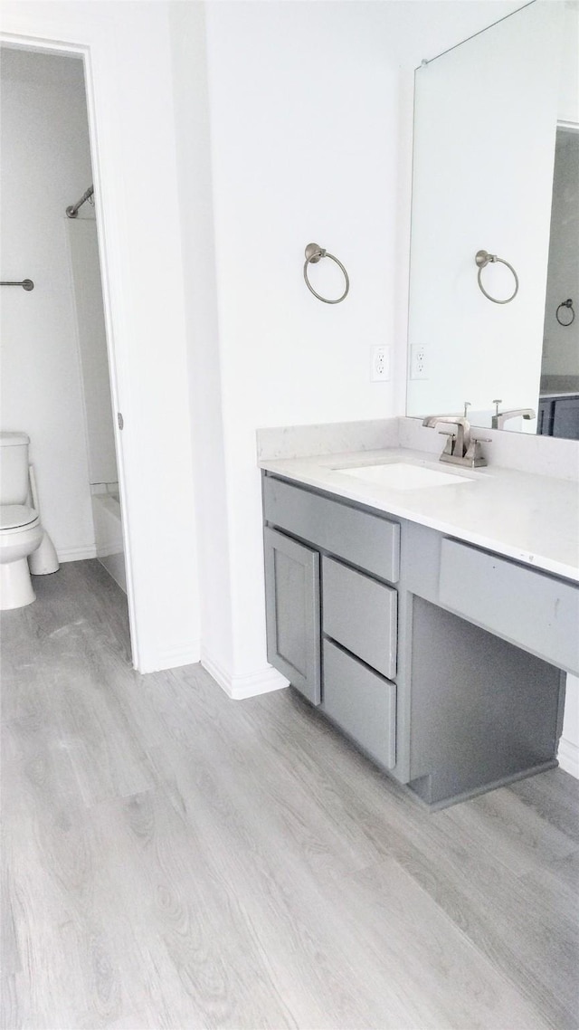 full bathroom with hardwood / wood-style flooring, vanity, tub / shower combination, and toilet