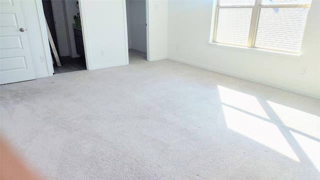 unfurnished bedroom featuring a spacious closet, light colored carpet, and a closet