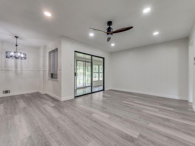 empty room with hardwood / wood-style flooring and ceiling fan with notable chandelier