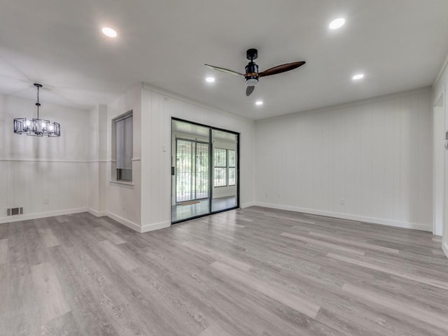 spare room with ceiling fan with notable chandelier, wood finished floors, visible vents, and recessed lighting