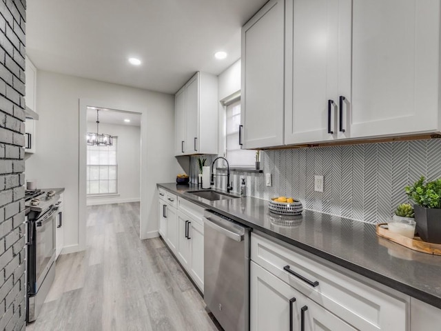 kitchen with dark countertops, appliances with stainless steel finishes, backsplash, and a sink