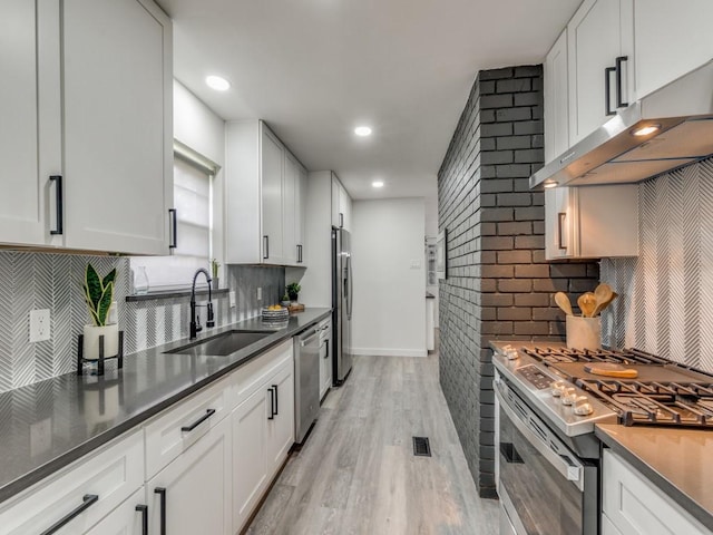 kitchen featuring visible vents, appliances with stainless steel finishes, extractor fan, light wood-style floors, and a sink