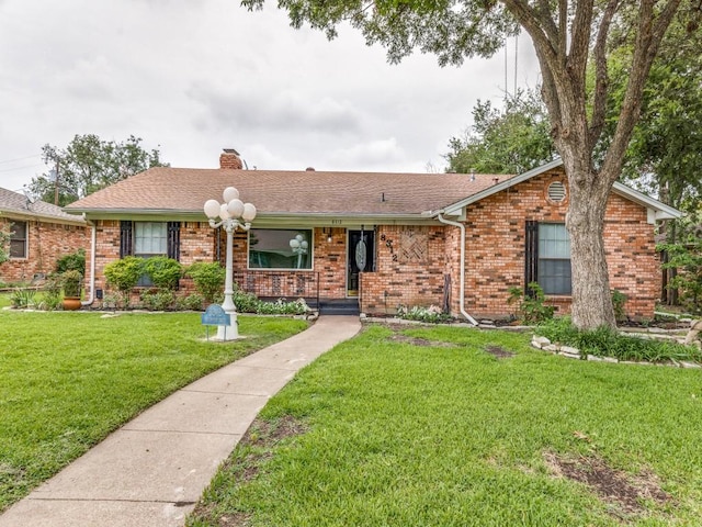 single story home with a front yard, a shingled roof, a chimney, and brick siding