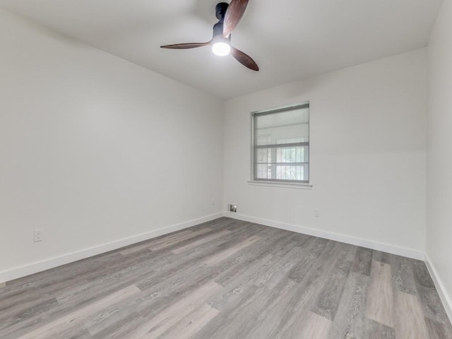 spare room featuring ceiling fan, baseboards, and wood finished floors