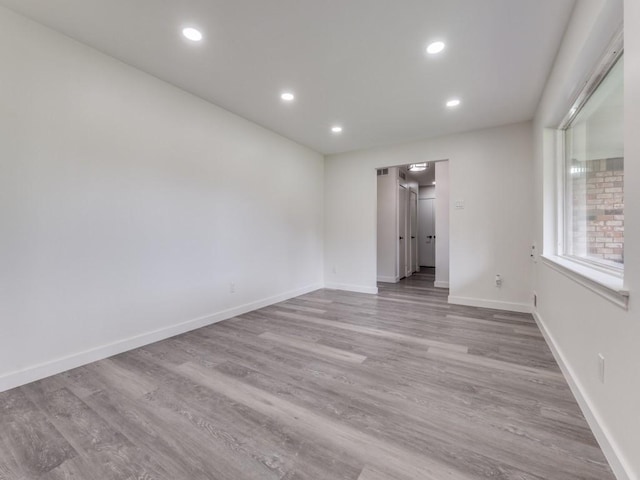 empty room featuring recessed lighting, wood finished floors, and baseboards