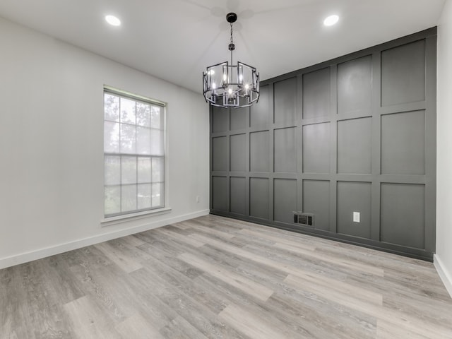 empty room featuring light hardwood / wood-style flooring and a chandelier