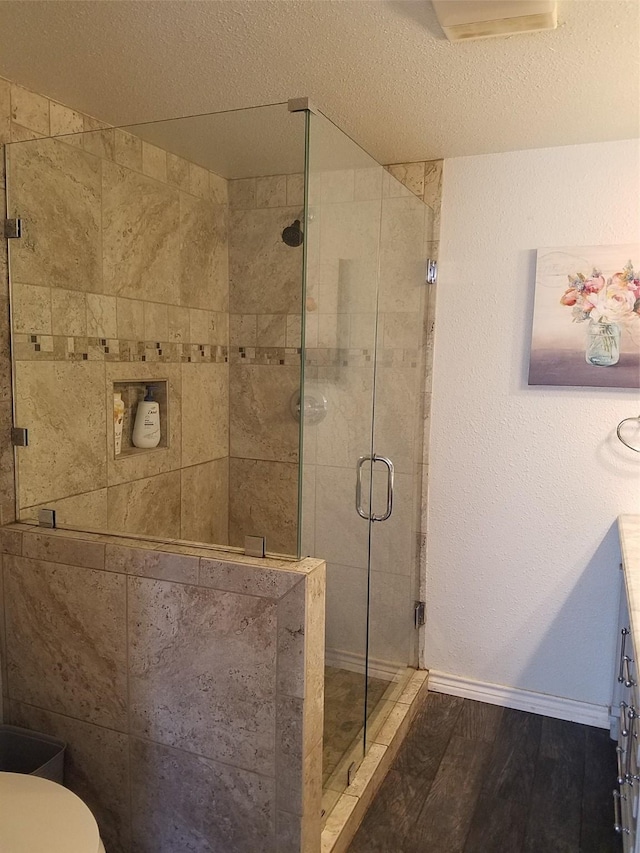 bathroom featuring hardwood / wood-style flooring, toilet, a textured ceiling, and walk in shower