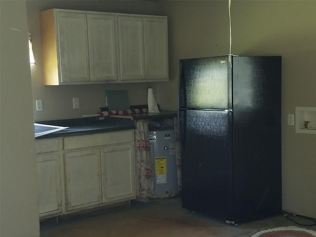 kitchen with water heater, white cabinetry, and black refrigerator