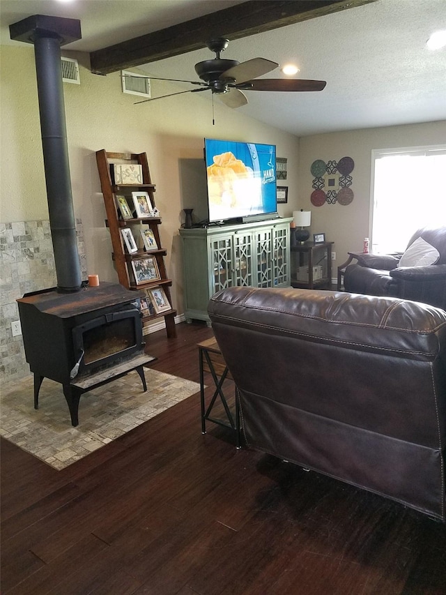 living room with ceiling fan, a wood stove, vaulted ceiling with beams, and dark hardwood / wood-style flooring