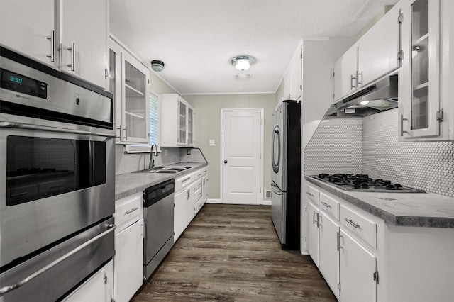 kitchen featuring dark wood-type flooring, sink, white cabinets, stainless steel appliances, and backsplash