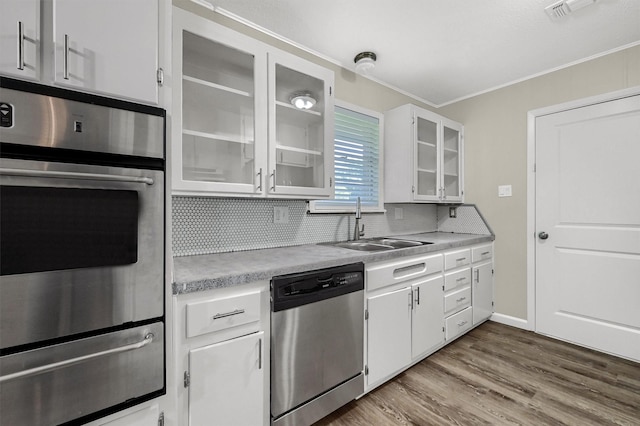 kitchen with sink, white cabinetry, stainless steel dishwasher, hardwood / wood-style flooring, and backsplash