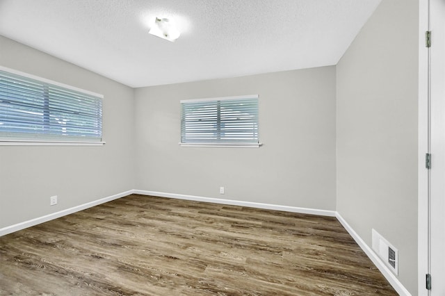 unfurnished room with plenty of natural light, dark hardwood / wood-style flooring, and a textured ceiling