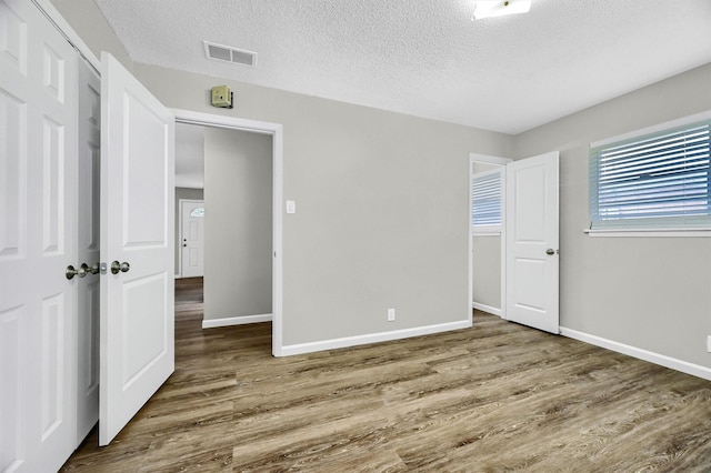 unfurnished bedroom with dark hardwood / wood-style flooring, a closet, and a textured ceiling