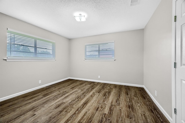 unfurnished room featuring dark wood-type flooring and a textured ceiling