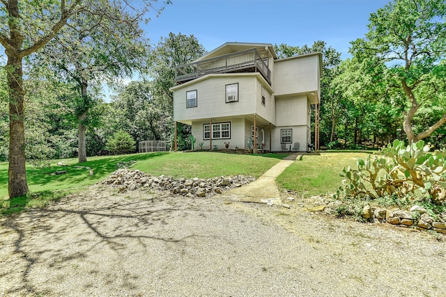 rear view of property with a balcony and a yard