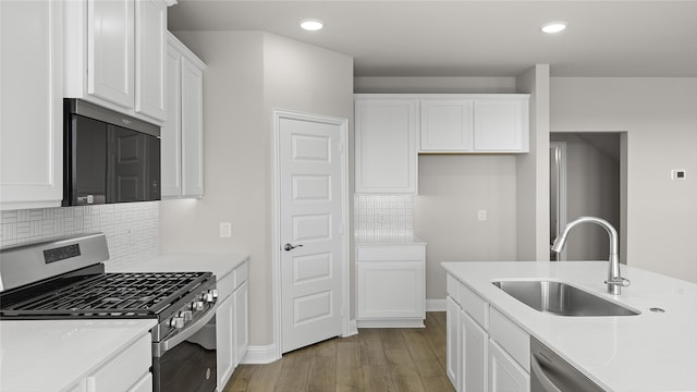 kitchen with white cabinets, a sink, light countertops, wood finished floors, and stainless steel appliances