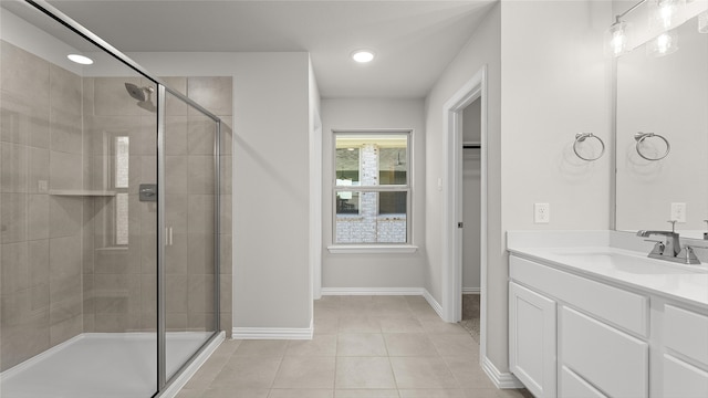 bathroom featuring tile patterned flooring, vanity, baseboards, and a stall shower