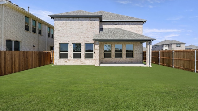 back of property featuring a yard, a fenced backyard, a patio area, and roof with shingles