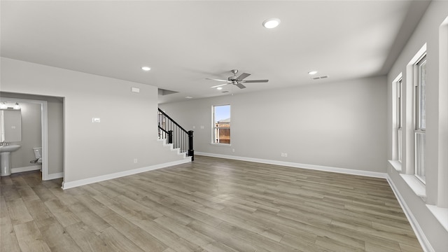 unfurnished living room featuring light wood-style flooring, baseboards, stairway, and recessed lighting