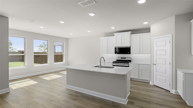 kitchen with a sink, visible vents, stainless steel gas range, and tasteful backsplash