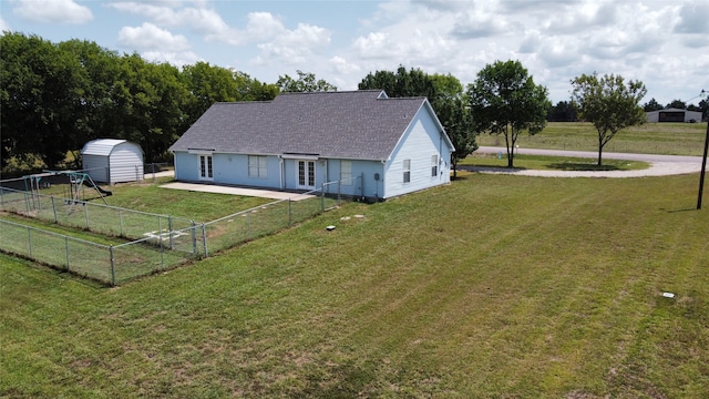 rear view of house with a storage shed and a lawn