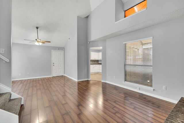 unfurnished living room featuring high vaulted ceiling, a textured ceiling, ceiling fan, and hardwood / wood-style floors