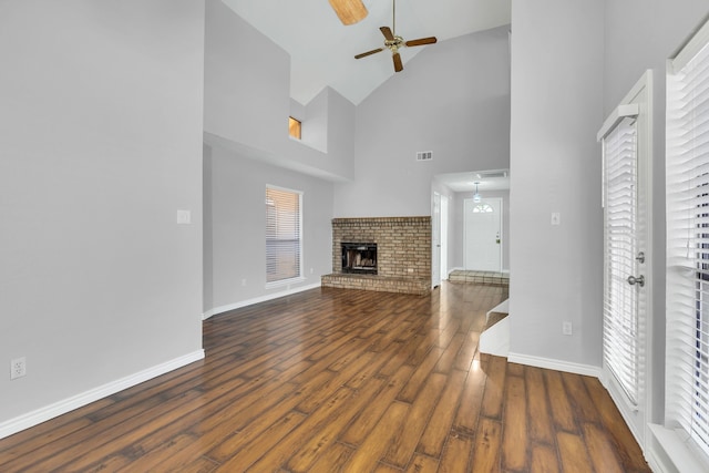 unfurnished living room with high vaulted ceiling, ceiling fan, dark hardwood / wood-style floors, and a brick fireplace