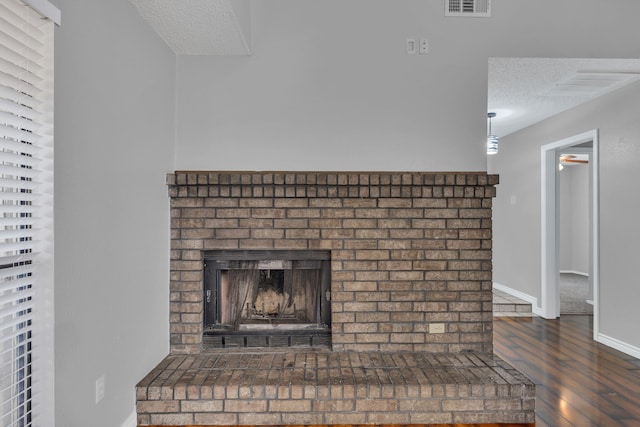 room details with a textured ceiling, a brick fireplace, and hardwood / wood-style flooring