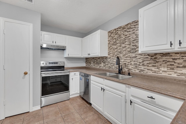 kitchen with appliances with stainless steel finishes, white cabinets, sink, backsplash, and light tile patterned flooring