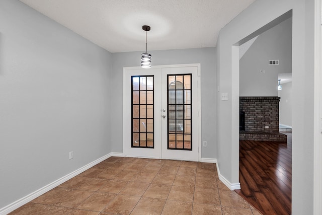 foyer featuring a fireplace, a textured ceiling, hardwood / wood-style flooring, and french doors