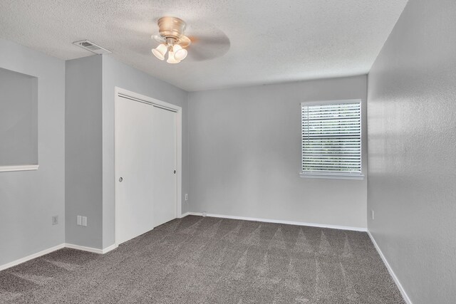 unfurnished bedroom with a closet, carpet, a textured ceiling, and ceiling fan